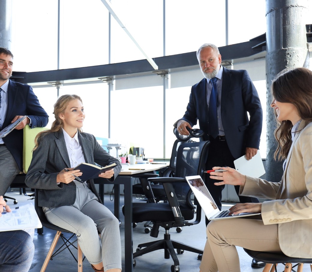 Fünfköpfiges Team bespricht sich in einem hellem Bürogebäude