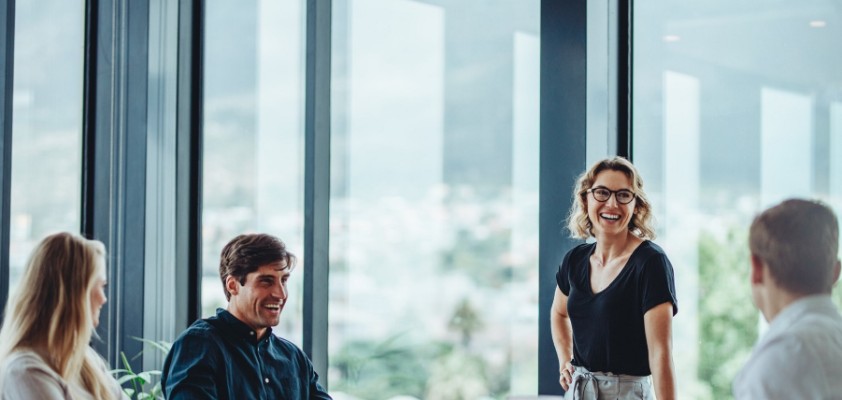 Ein vierköpfiges Team diskutiert in einem hellem Büro mit großen Fenstern